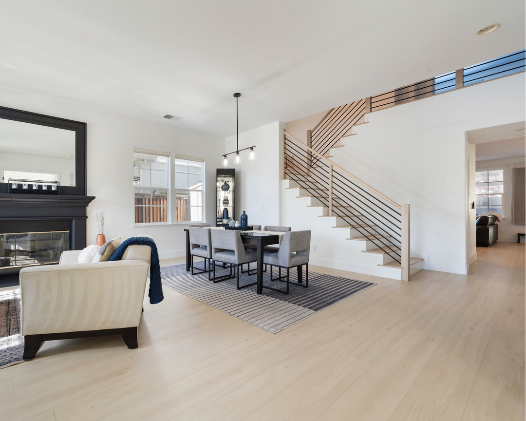 Modern living room with white walls, wooden floor, and staircase.