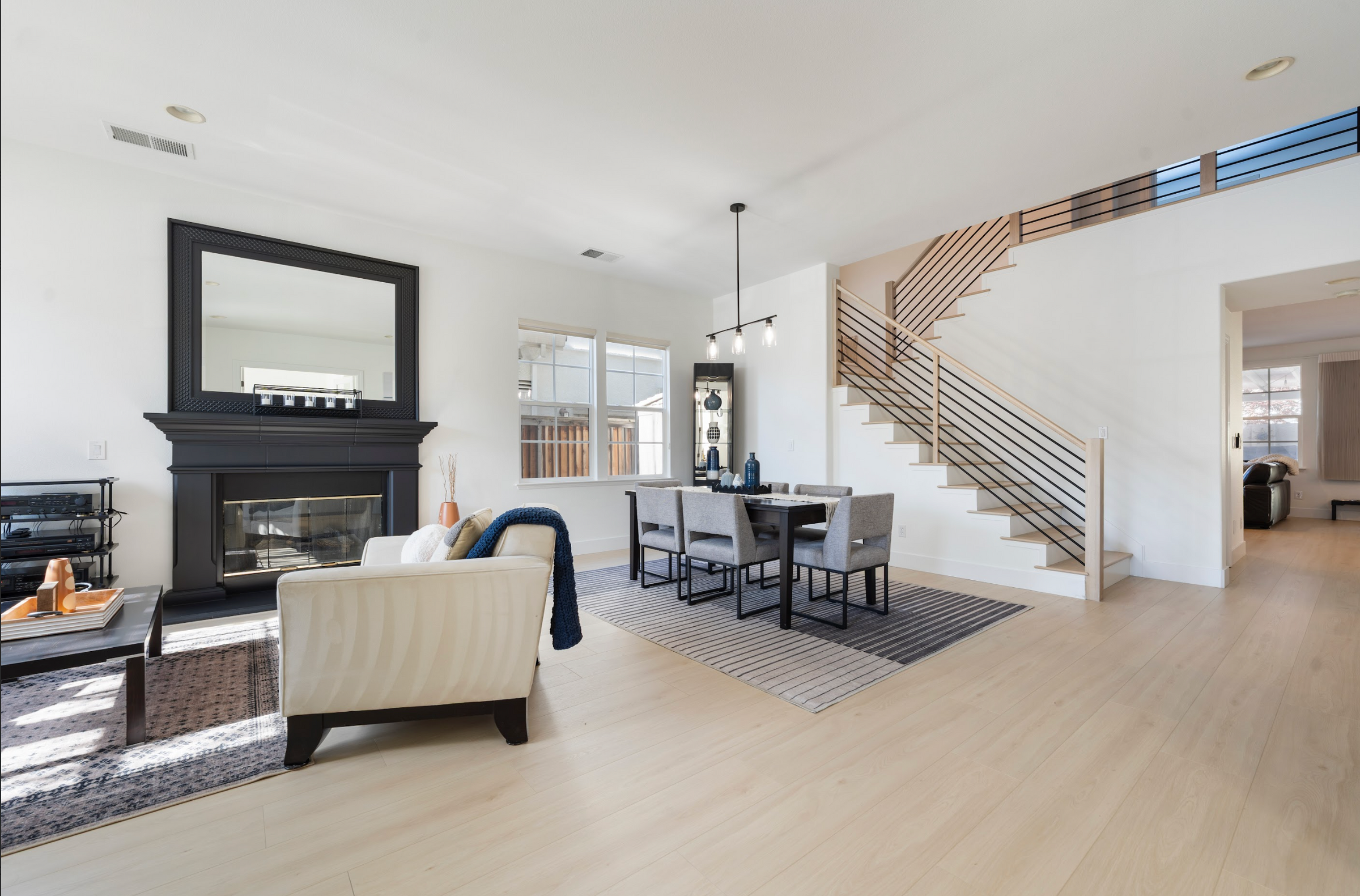 Modern living room with a fireplace, dining table, and staircase.